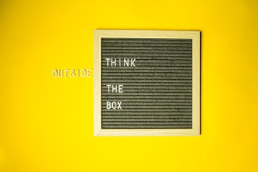 A square frame with the words 'Think outside the box' on a bright yellow background.
